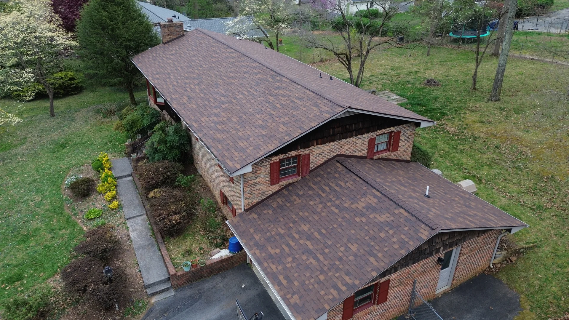 Aerial view of a completed brown shingle roof framed by East Tennessee greenery