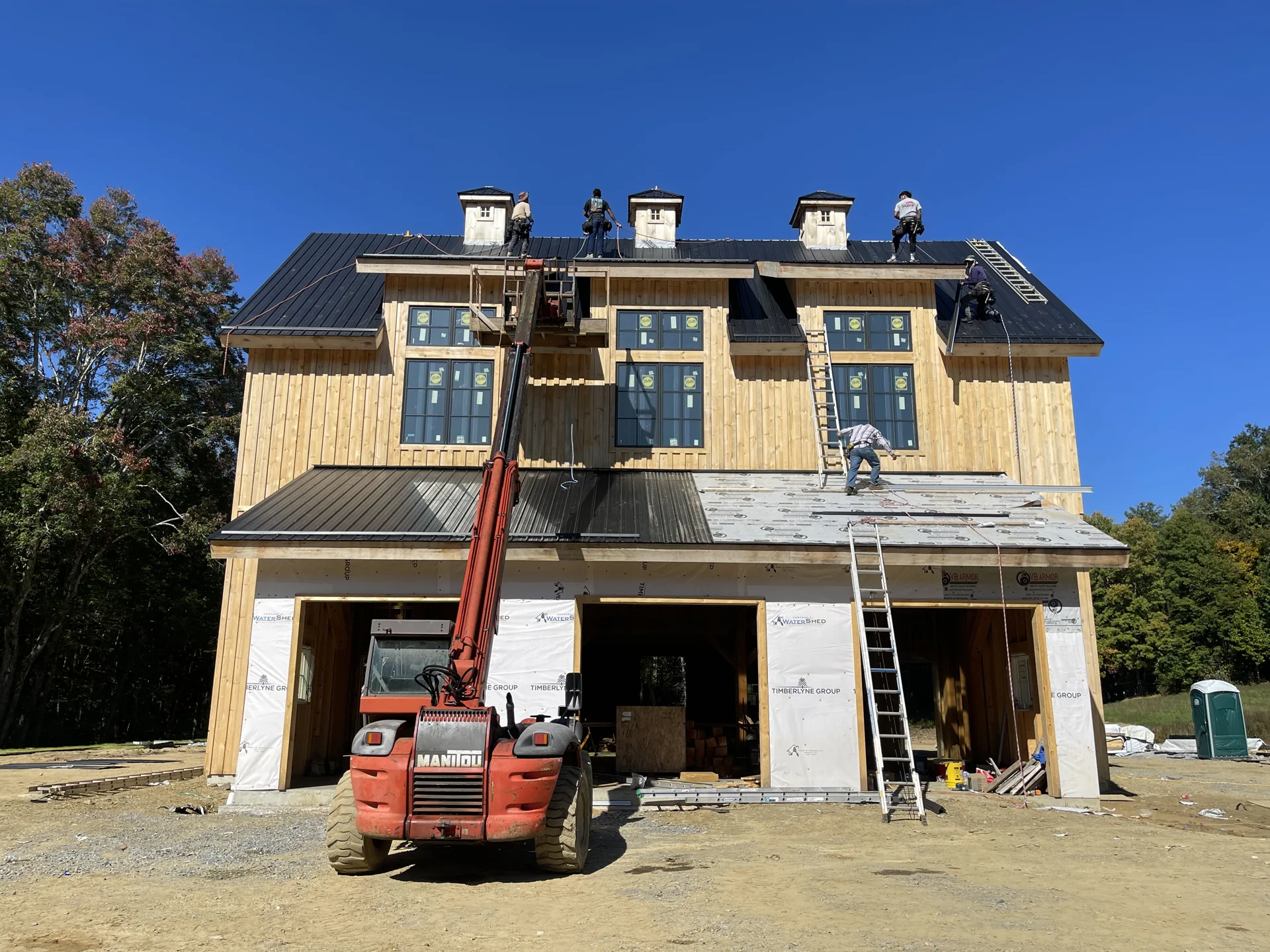 Multi-story house under construction with crew working at the roofline