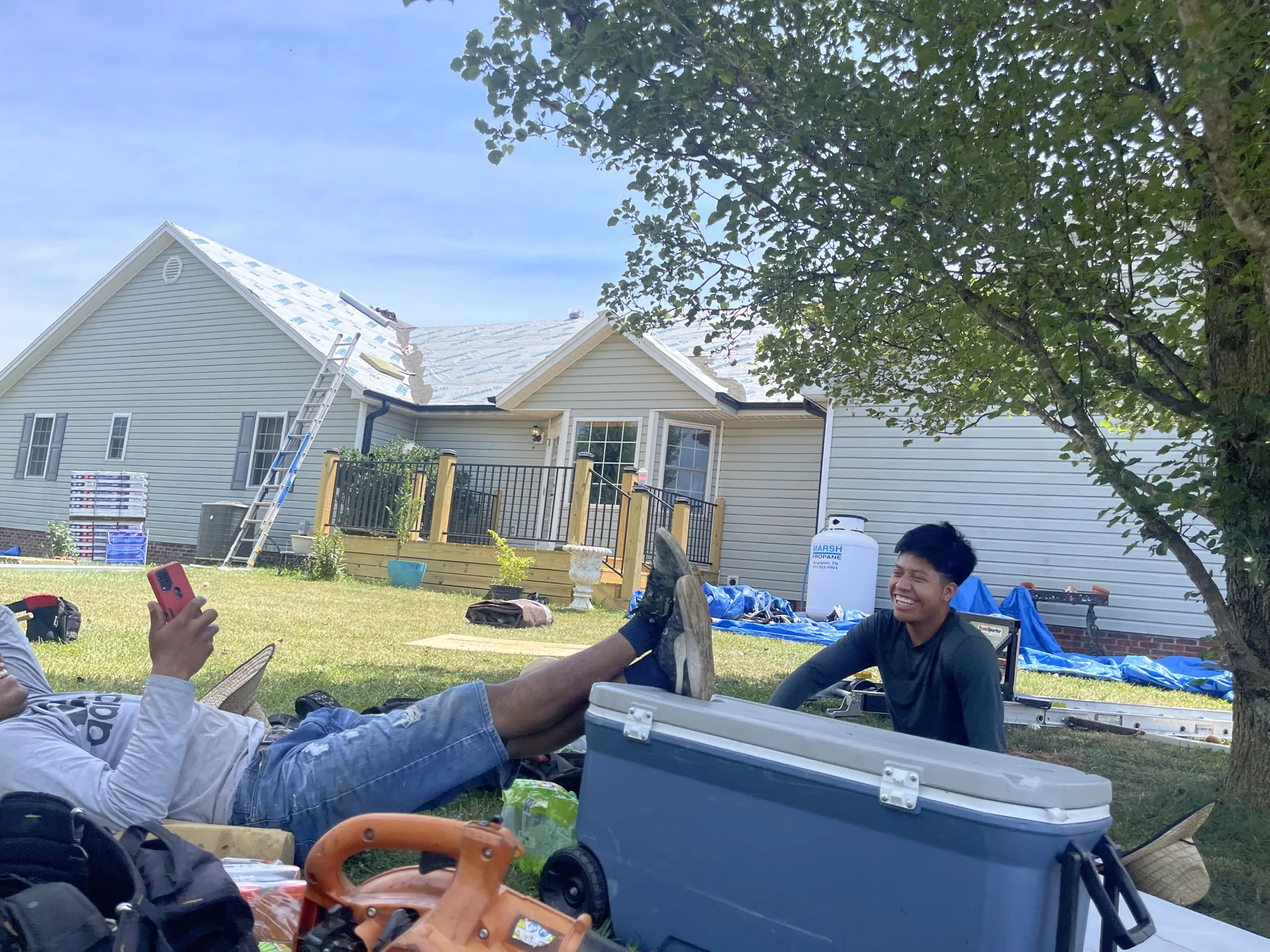 Crew member near roofing materials and equipment at a residential project