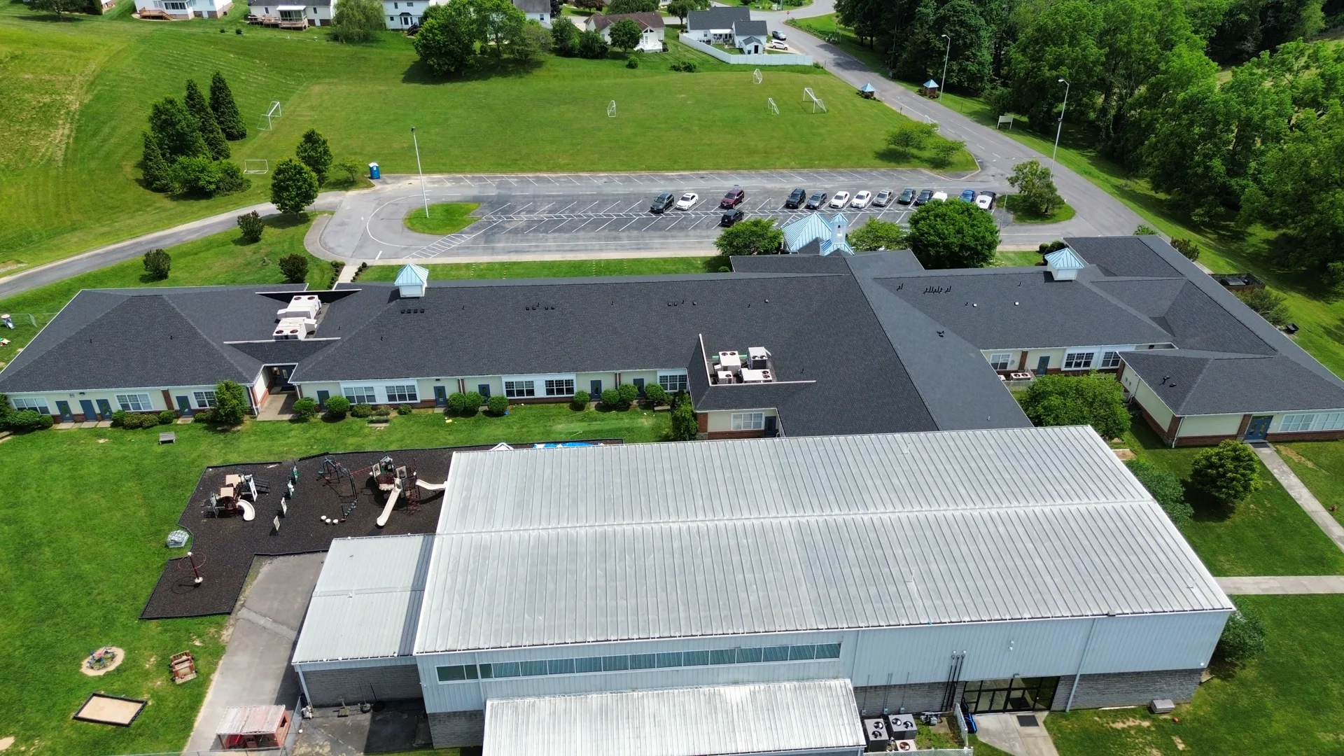 Aerial view of a large low-slope roof and adjoining metal-roofed structure